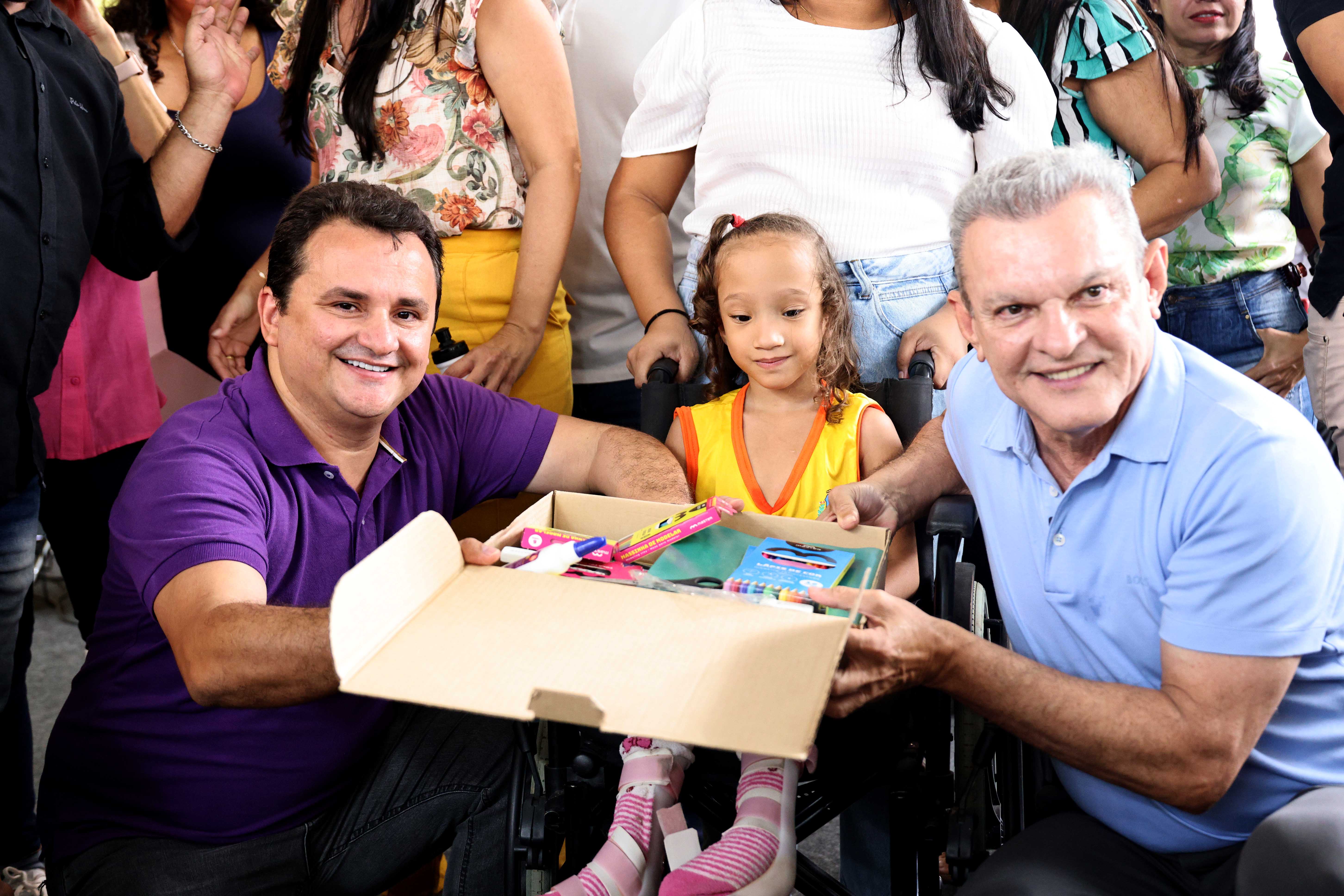 prefeito e secretário entregando kit escolar a criança